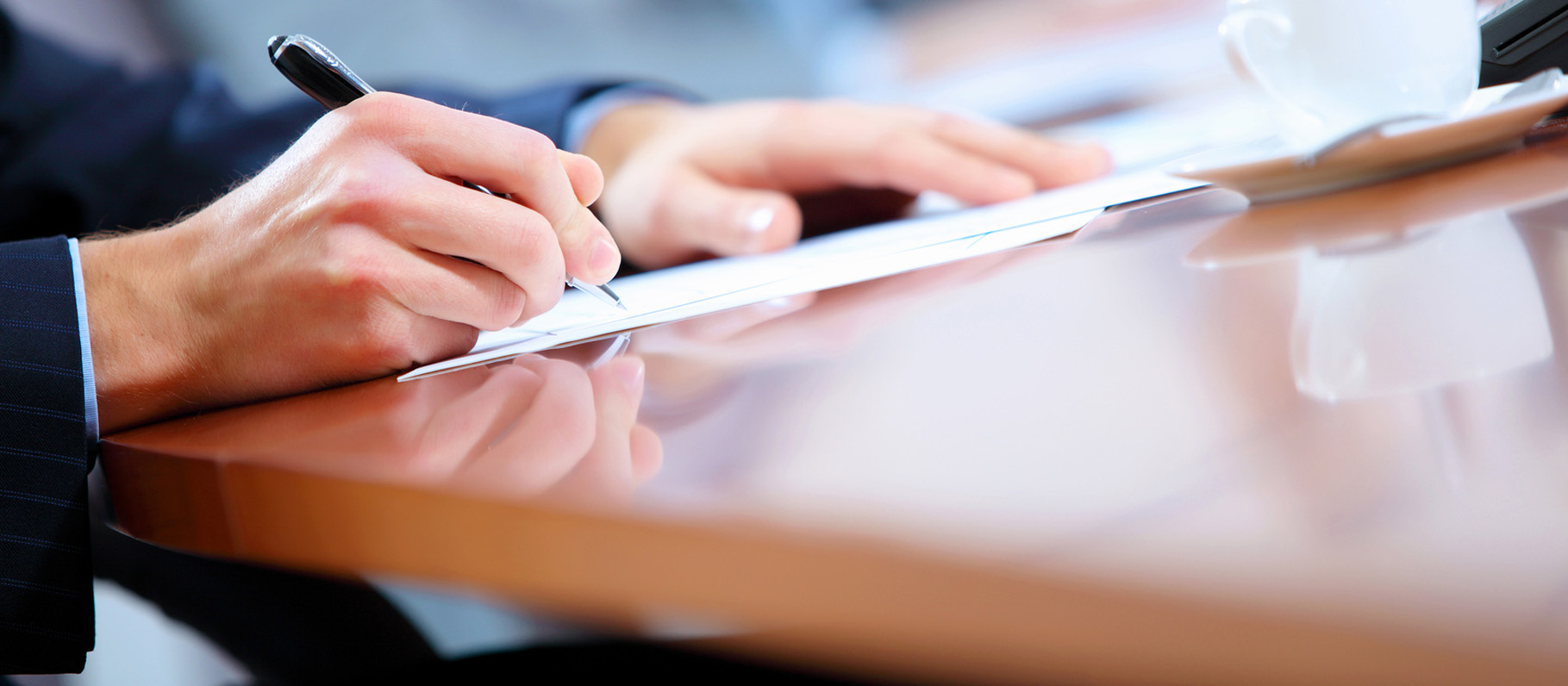 Image of person in suit signing paperwork